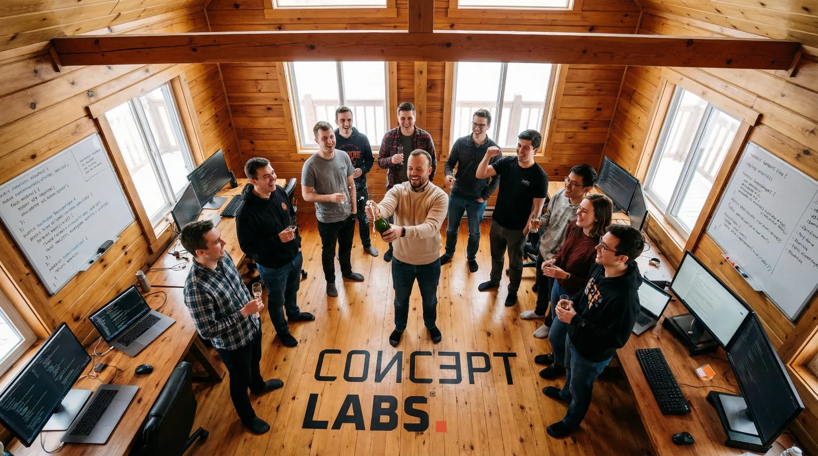 Overhead view of the ConceptLABS team in their workspace, surrounded by whiteboards with code and planning diagrams